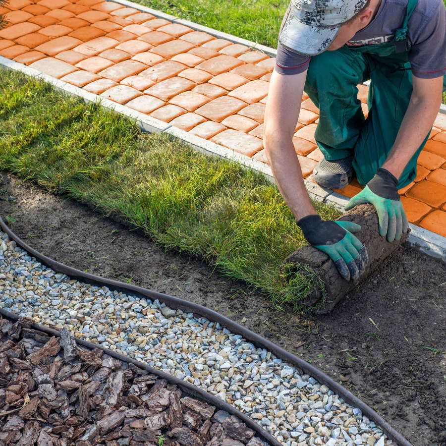 Hands setting paver edging on a compacted base