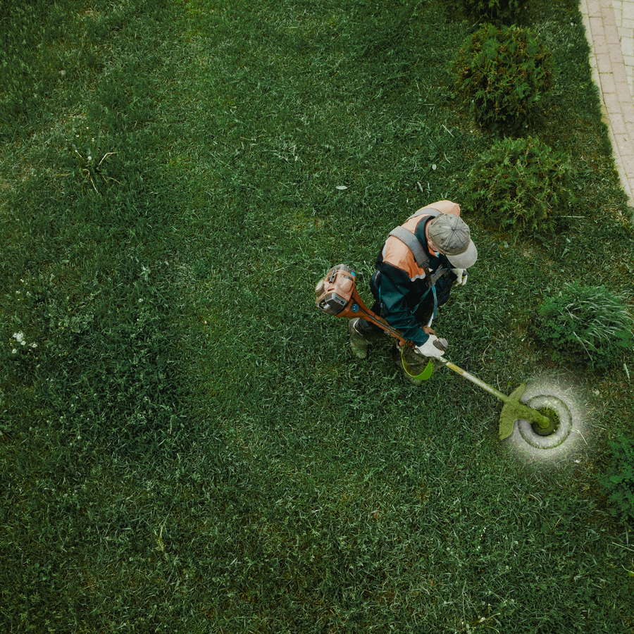 A crew member trimming the edge of a lawn